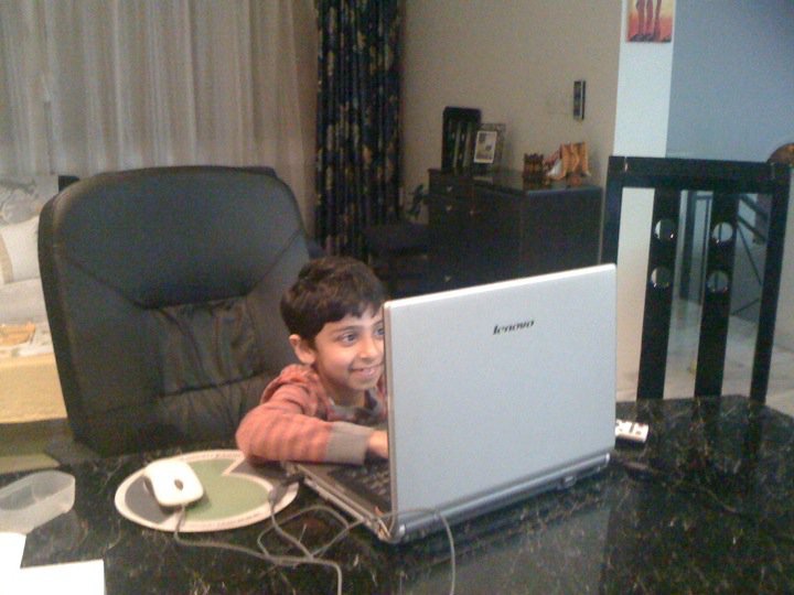 Tanay as a child, sitting at a laptop